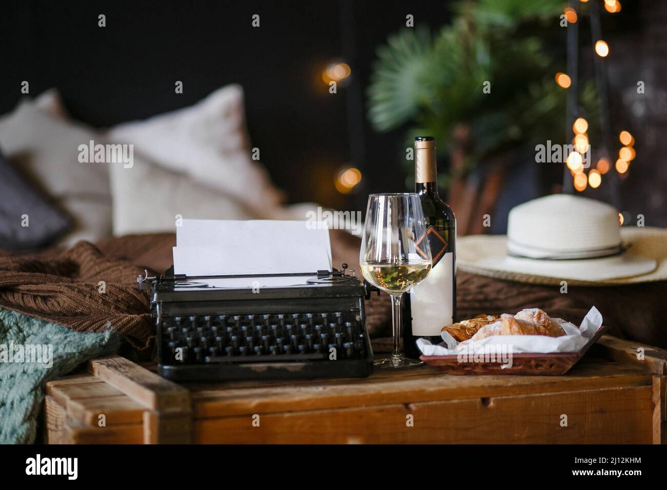 Die Inspiration eines Schriftstellers, der Texte auf einer Vintage-Schreibmaschine schreibt, Freelancer Breakfast Croissants und Wein, Office im Loft-Stil Stockfoto
