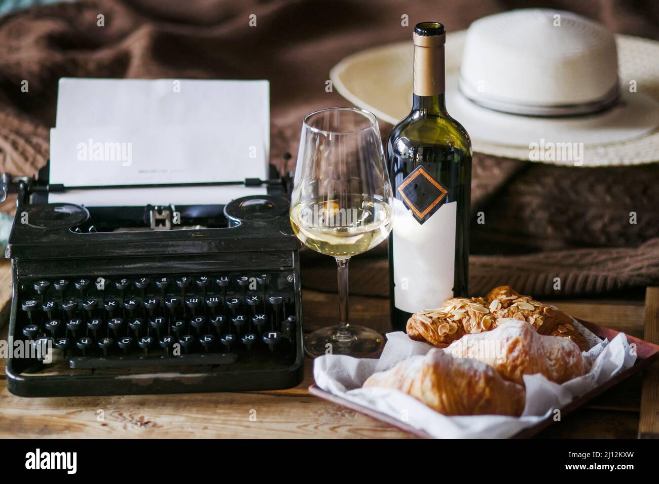 Die Inspiration eines Schriftstellers, der Texte auf einer Vintage-Schreibmaschine schreibt. Freelancer Frühstück Croissants und Wein. Büro im Loft-Stil Stockfoto