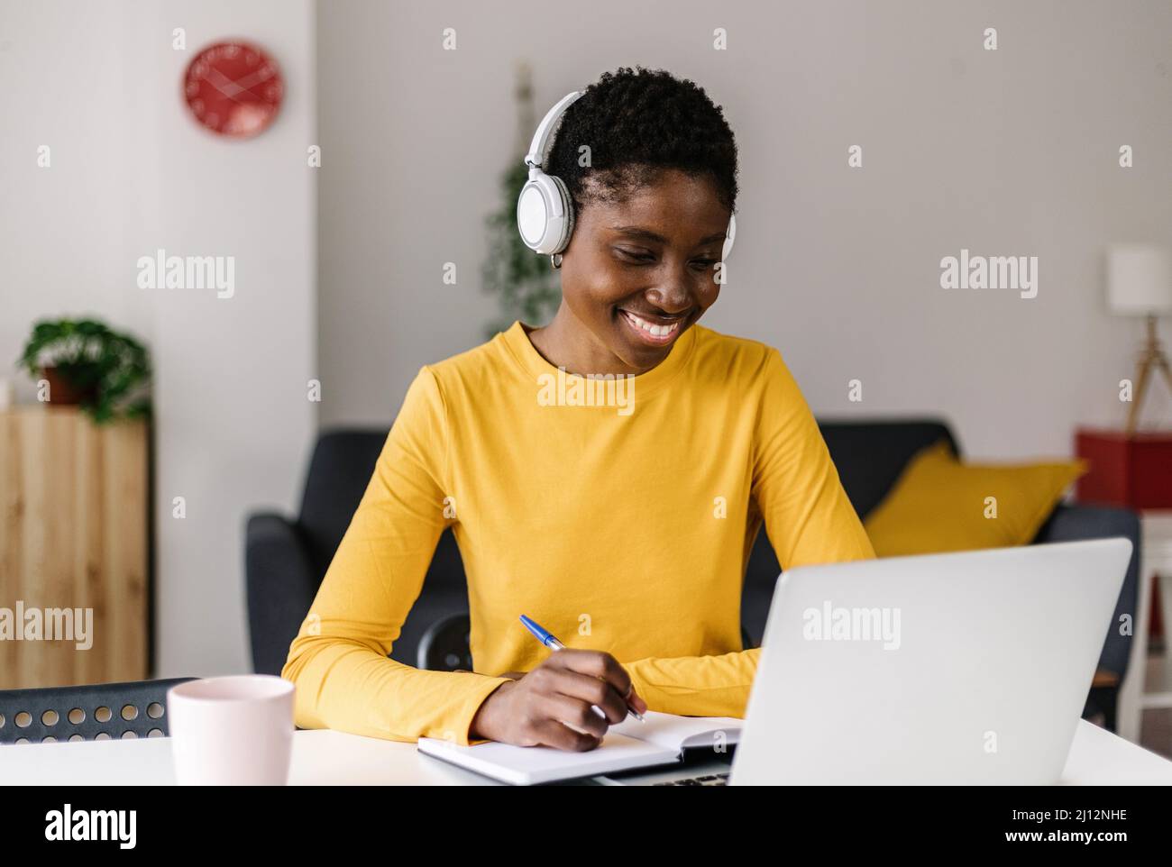 Junge afrikanische Frau, die von zu Hause aus am Laptop arbeitet Stockfoto