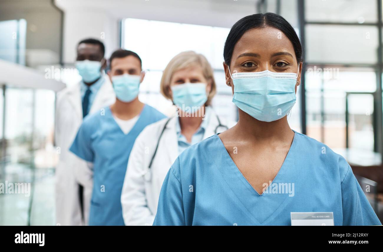 Als medizinisches Fachpersonal haben wir eine so wichtige Aufgabe vor uns. Porträt einer Gruppe von Ärzten, die Gesichtsmasken tragen, während sie zusammen stehen Stockfoto