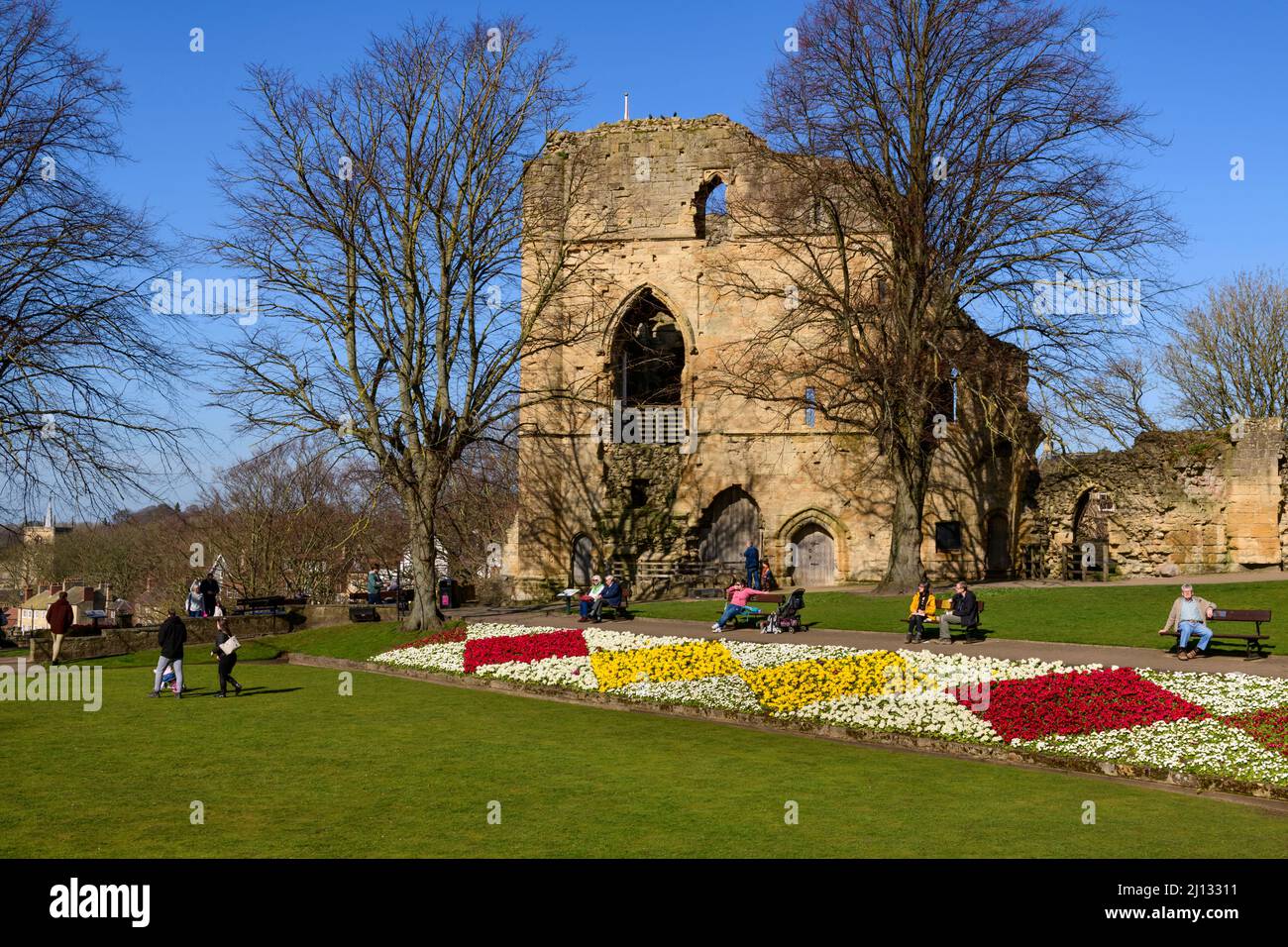 Menschen sitzen entspannt Sonne genießen (helle Border Blumen, alten Turm halten Ruinen, blauer Himmel) - Knaresborough Castle, North Yorkshire, England, Großbritannien. Stockfoto