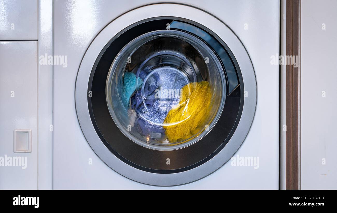 Bunte Wäsche in einer Frontlader-Waschmaschine Stockfoto