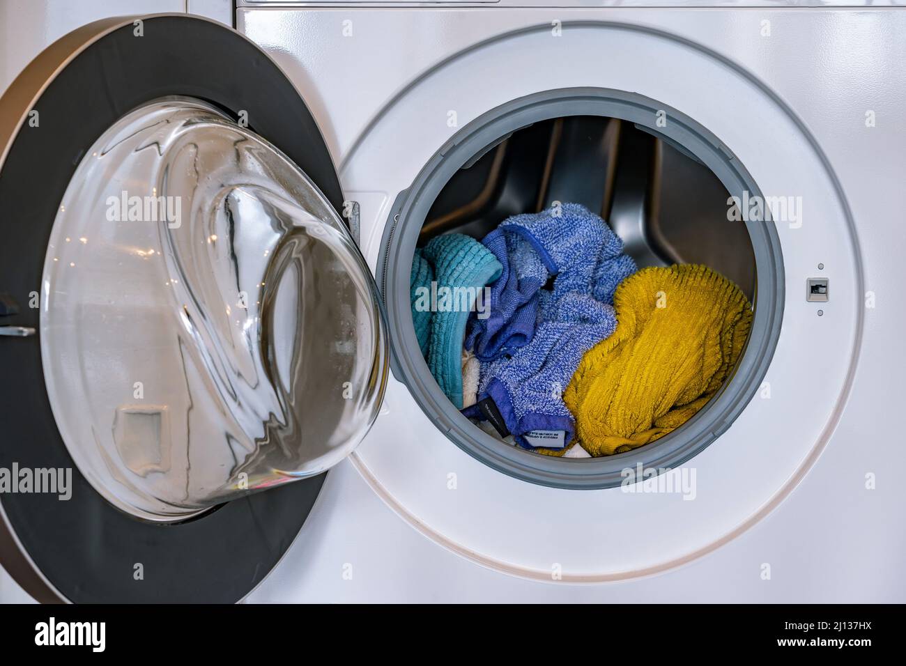Bunte Wäsche in einer Frontlader-Waschmaschine Stockfoto