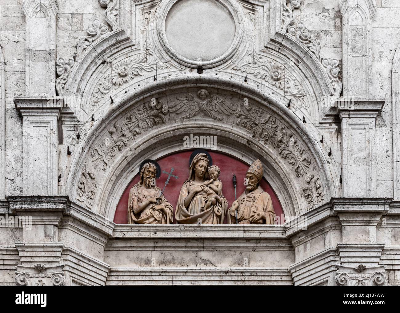 Teil der Marmorfassade mit dem Terrakotta-Relief im Tympanon über der Tür der Renaissance Sant Agostino Kirche, Montepulciano, Siena, Italien Stockfoto