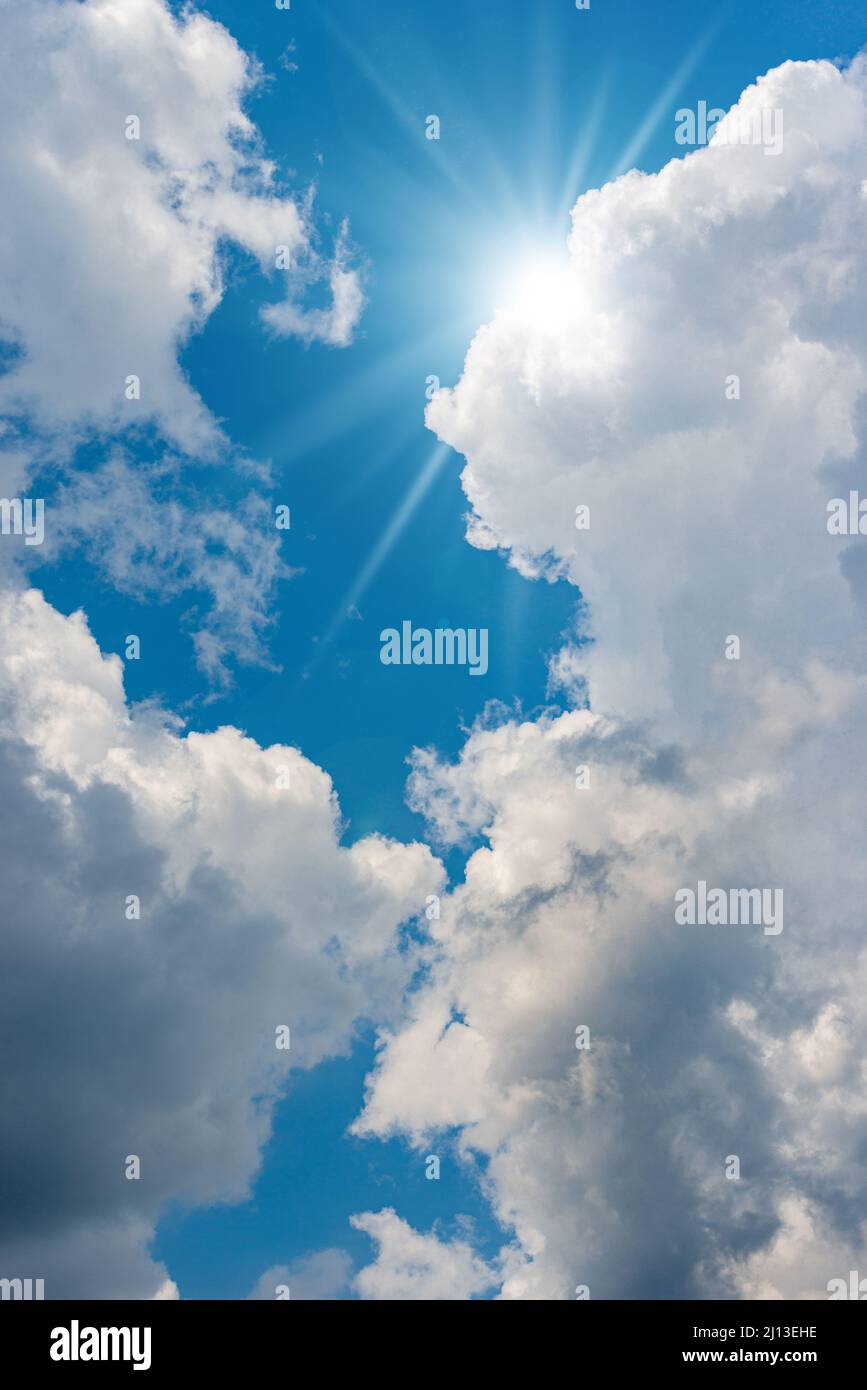 Schöner blauer Himmel mit weißen Kumuluswolken und Sonnenstrahlen (Sonnenstrahlen). Hintergrundfotografie. Stockfoto