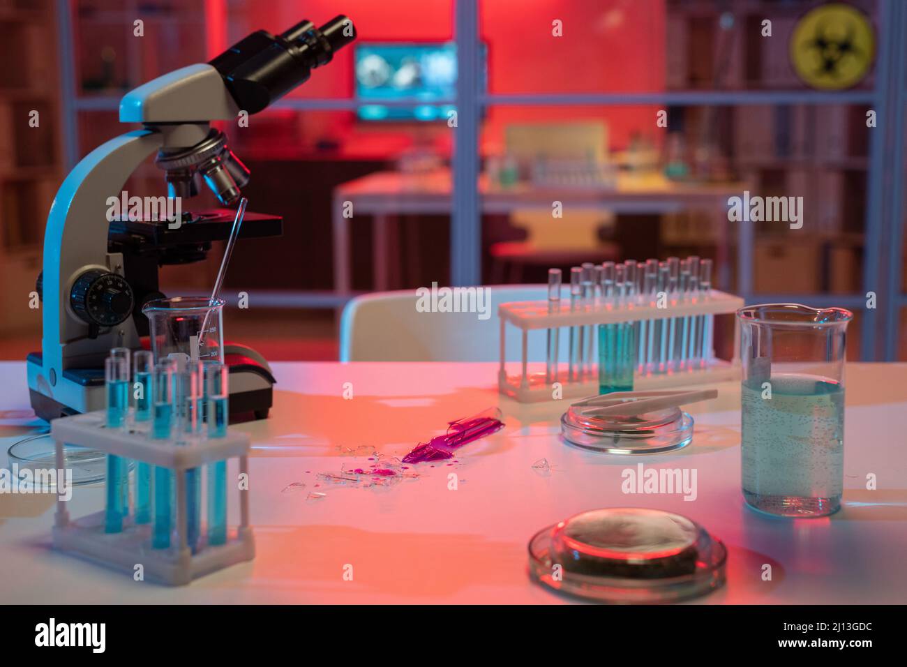 Gebrochene Flasche mit flüssigem gefährlichen Erreger am Arbeitsplatz des modernen Wissenschaftlers oder Virologen im Kliniklabor Stockfoto