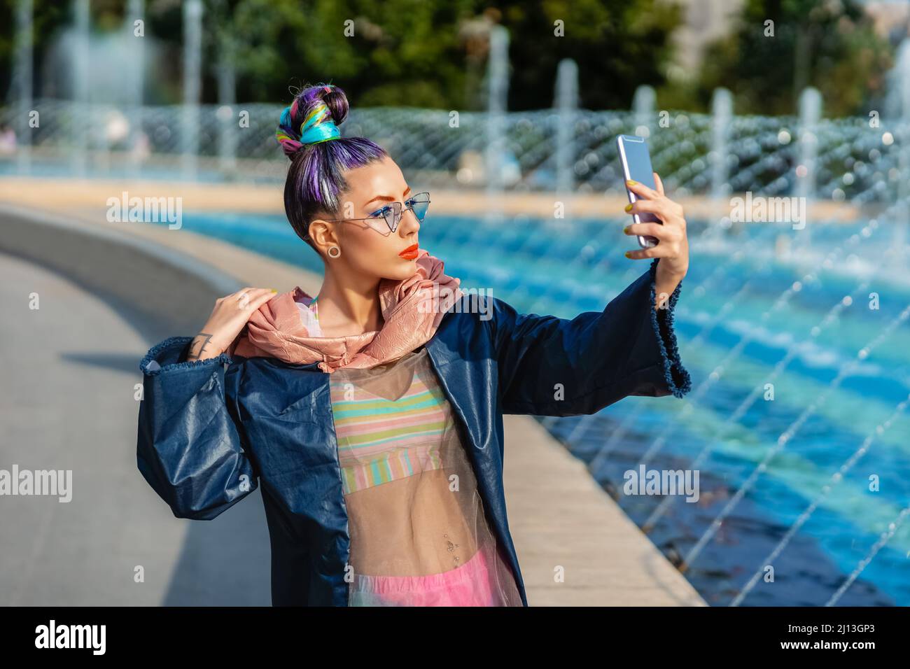 Verspieltes cooles hippy junges Mädchen mit Kopfhörern und verrückten Haaren, die selfie auf der Straße einnehmen Stockfoto