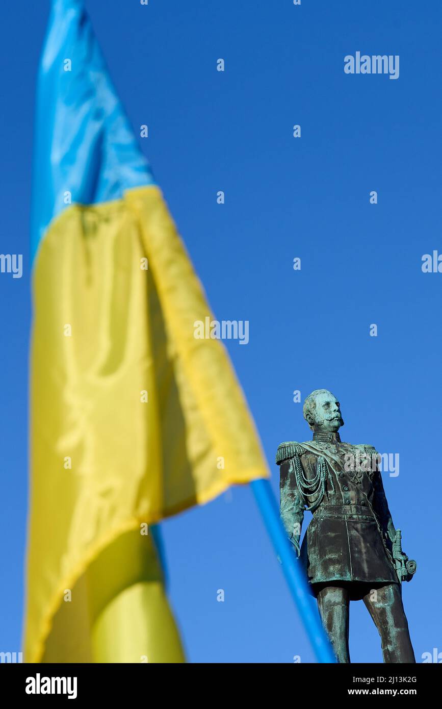 Helsinki, Finnland - 26. Februar 2022: Statue des ehemaligen russischen Zaren Alexander II und ukrainischer Flagge bei einer Kundgebung gegen die russischen Militärankaten Stockfoto