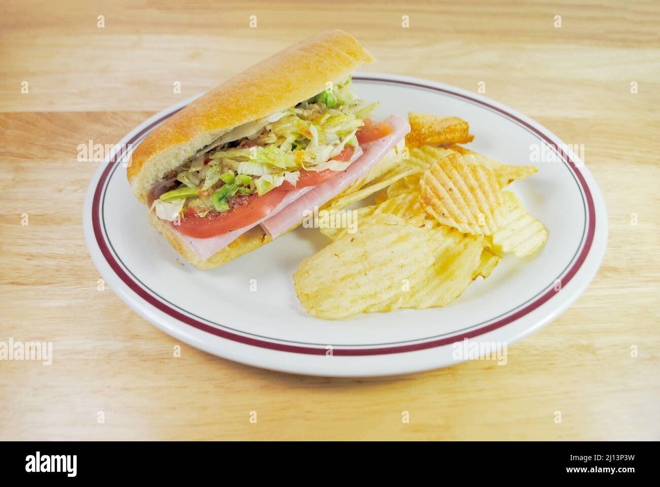 Ein Sub Sandwich mit Kartoffelchips serviert als kaltes Mittagessen Stockfoto