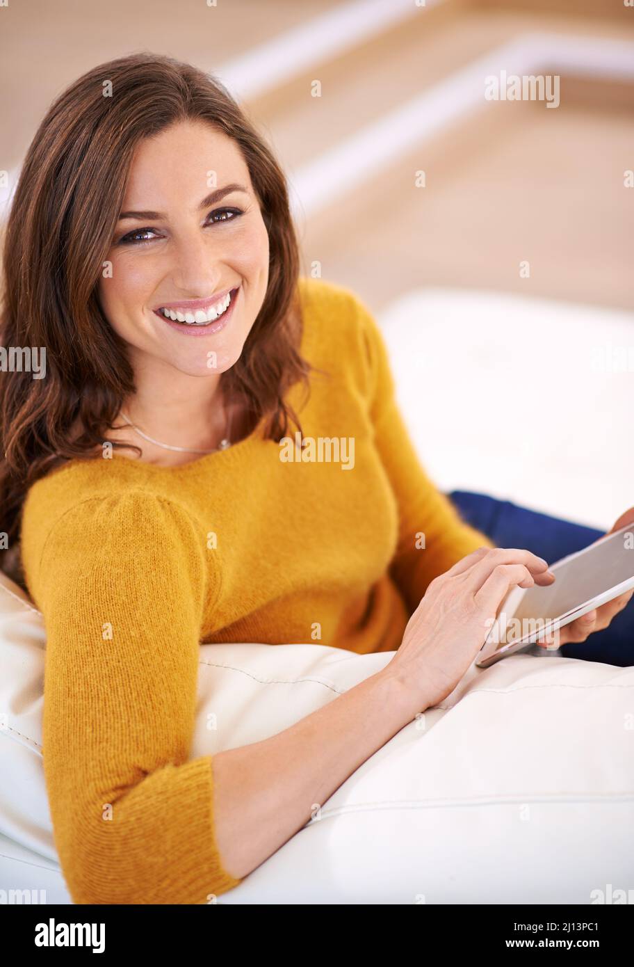 Auf ihrem digitalen Tablet in ein gutes Buch zu kommen. Aufnahme einer wunderschönen jungen Frau mit einem digitalen Tablet in Innenräumen. Stockfoto