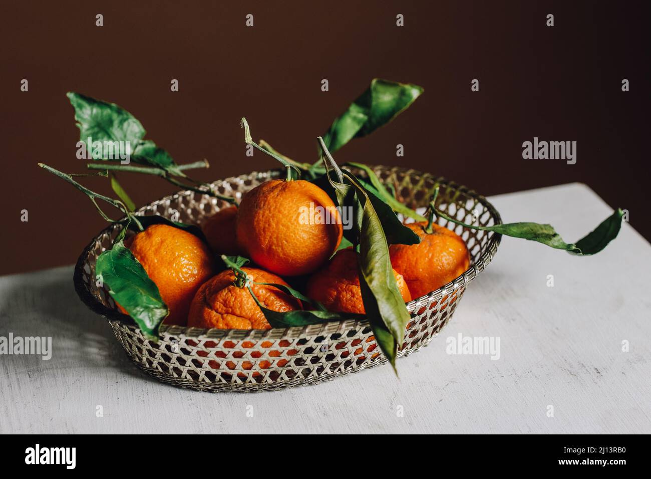 mandarinorangen im Korb mit braunem Hintergrund Stockfoto