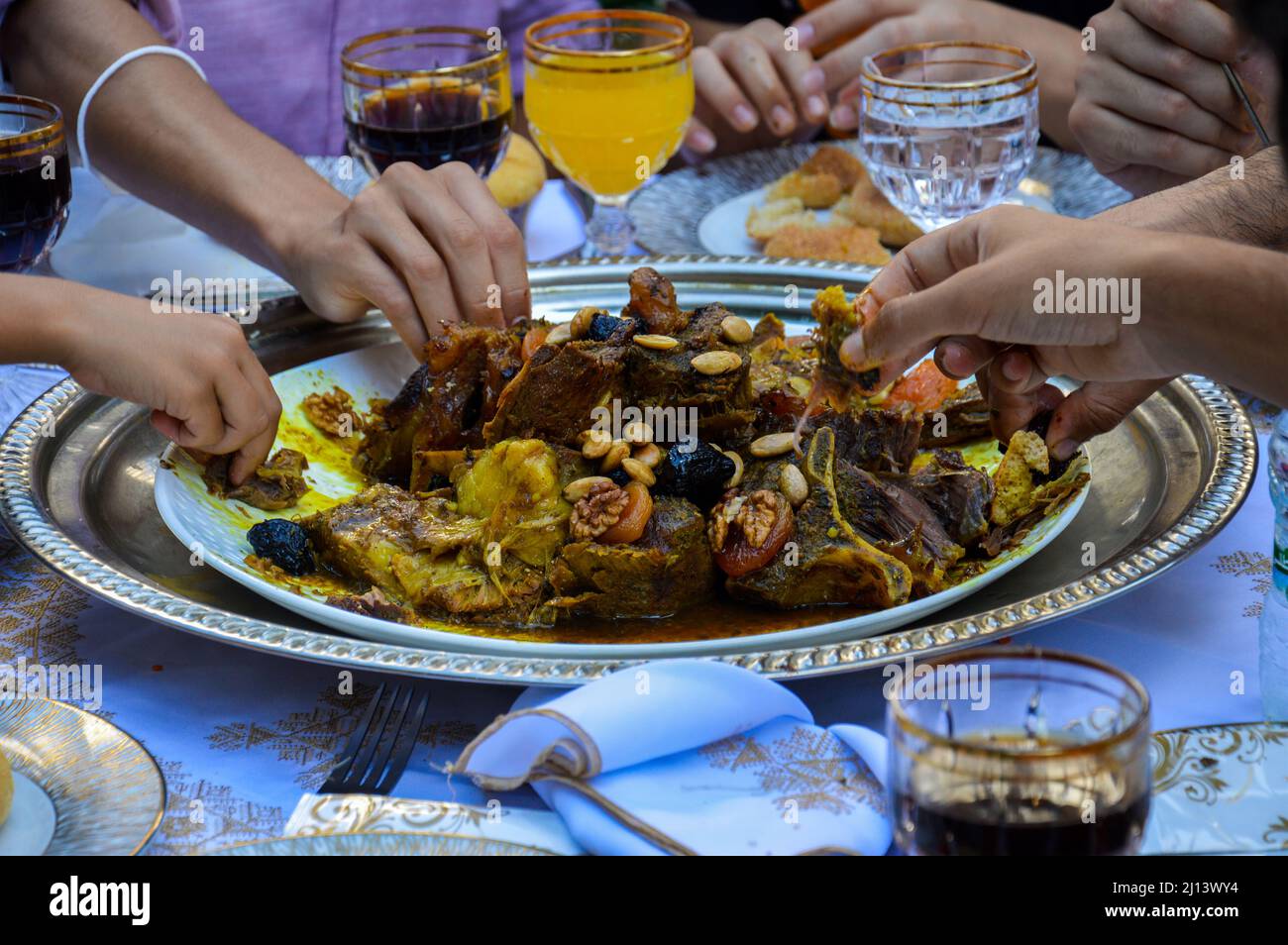 Marokkanisches Essen. Fleischschale mit getrockneten Pflaumen und verzehrfertigen Händen Stockfoto