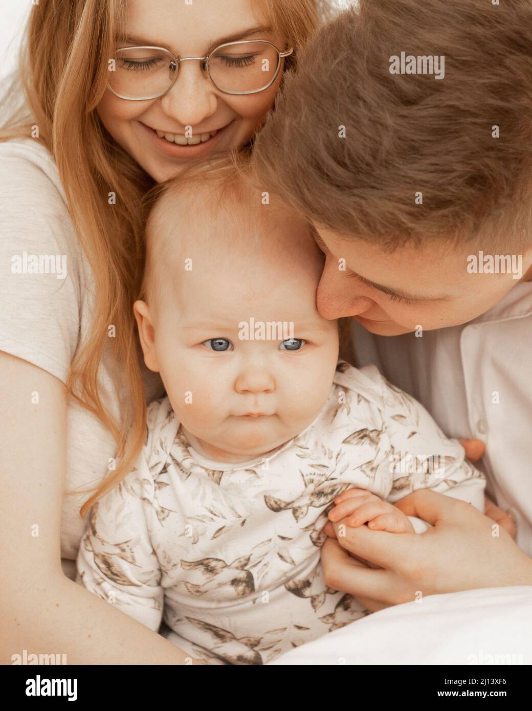 Porträt von fröhlich lächelnd gemütlich und verheirateten Paar. Frau in Brille, Mann, Baby. Schutz und Unterstützung von Kindern in der Familie Stockfoto