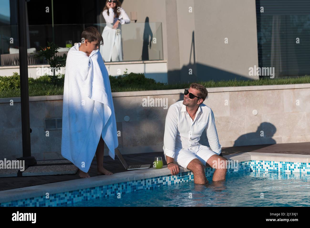 Glückliche Familie genießt Urlaub in einem luxuriösen Haus mit Pool. Das ältere Paar verbringt während der Ferien Zeit mit seinem Sohn. Selektiver Fokus Stockfoto