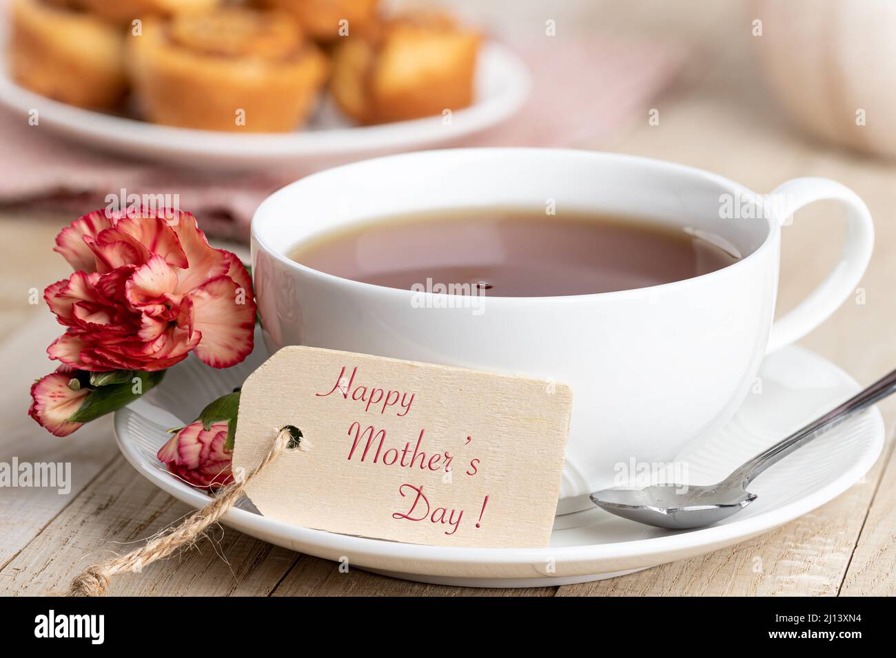 Happy Mothers Day Tag und eine Tasse Tee mit roter Nelke auf einem Holztisch Stockfoto
