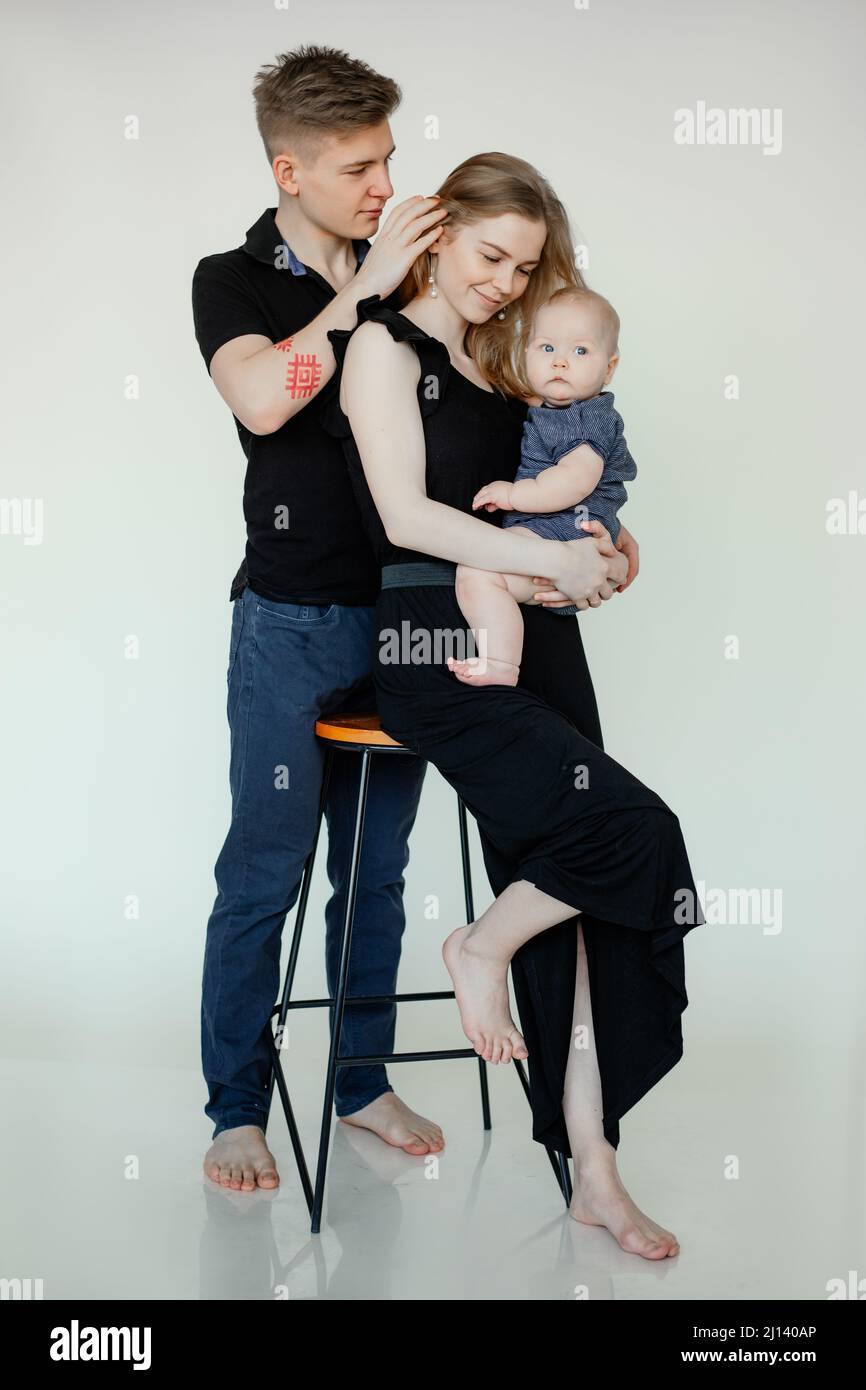 Vertikale Aufnahme von sorglosen glücklichen Ehepartnern, barfuß-Familie, Mann, Frau, Kind auf Barstuhl. Fürsorgliches und liebevolles Konzept Stockfoto