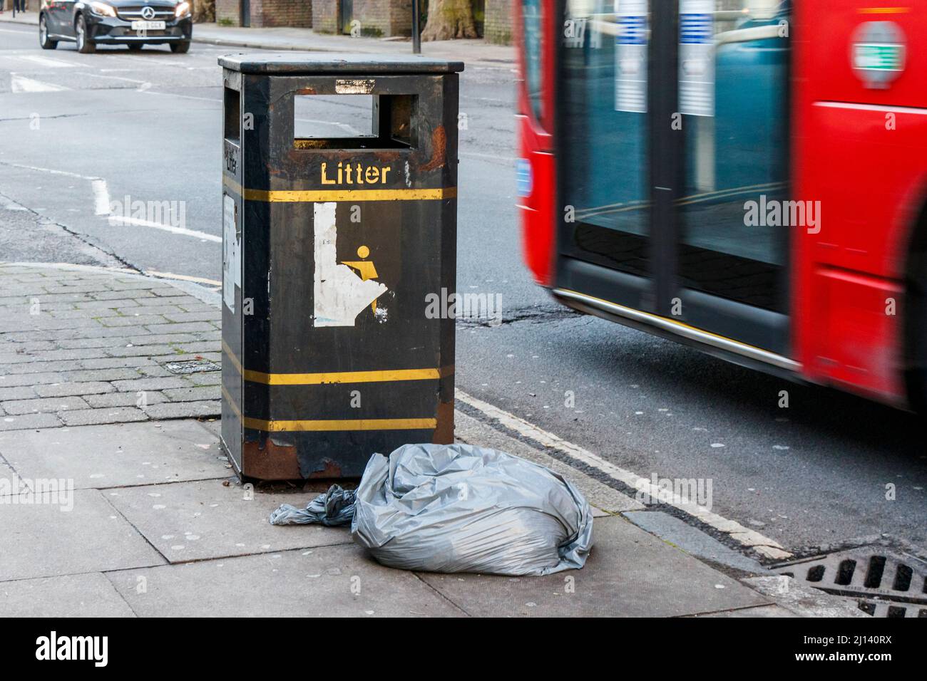 Eine Mülltüte neben einem Abfalleimer, London, Großbritannien Stockfoto