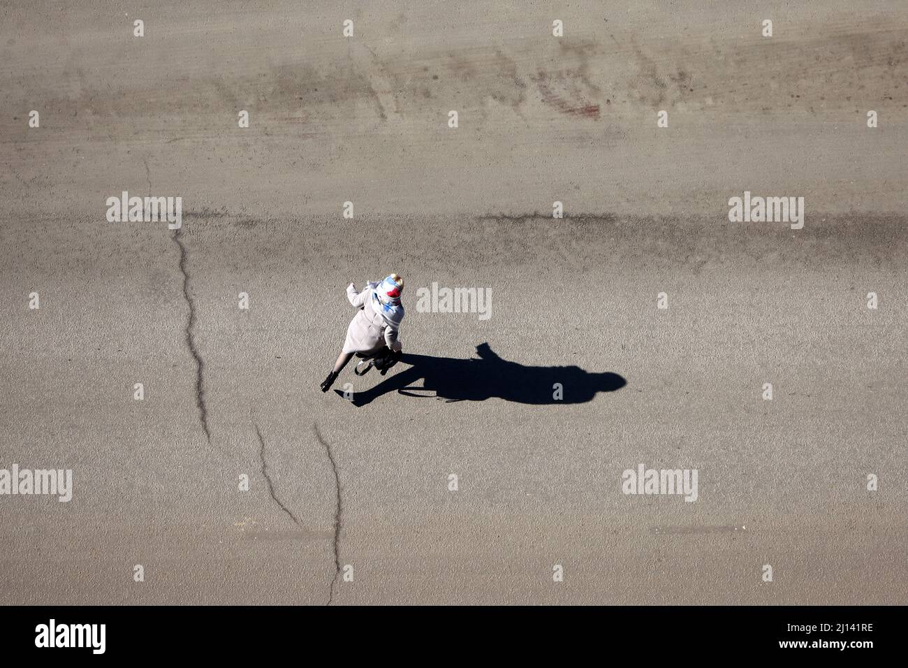 Laufende Frau überquert die Straße, Draufsicht. Langer Schatten auf Asphalt, Konzept der Verkehrssicherheit Stockfoto