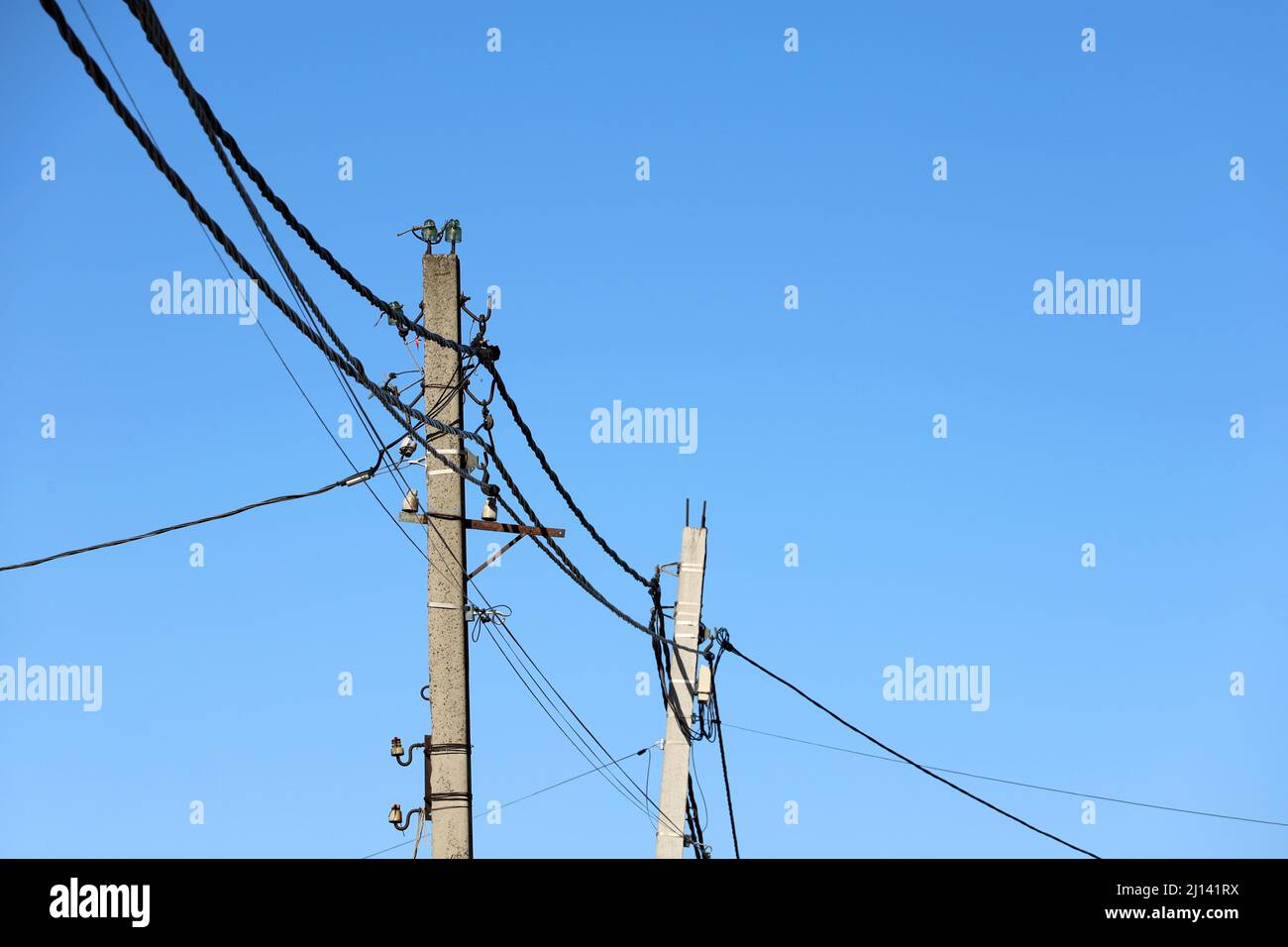 Stromleitungsmasten mit verwickelten elektrischen Drähten und Kondensatoren auf blauem Himmel Hintergrund. Stromübertragungsleitung, Stromversorgung Stockfoto