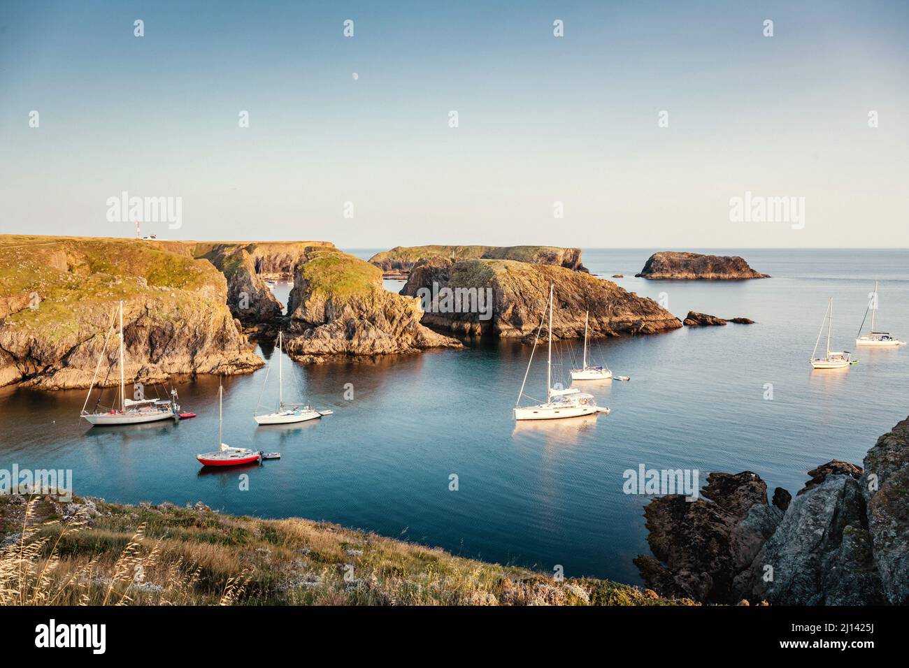 Die ruhigen Buchten an der felsigen Küste der Insel Belle Ile en Mer bieten einen geschützten Ankerplatz für viele Segelboote im ruhigen Sonnenuntergang. Stockfoto