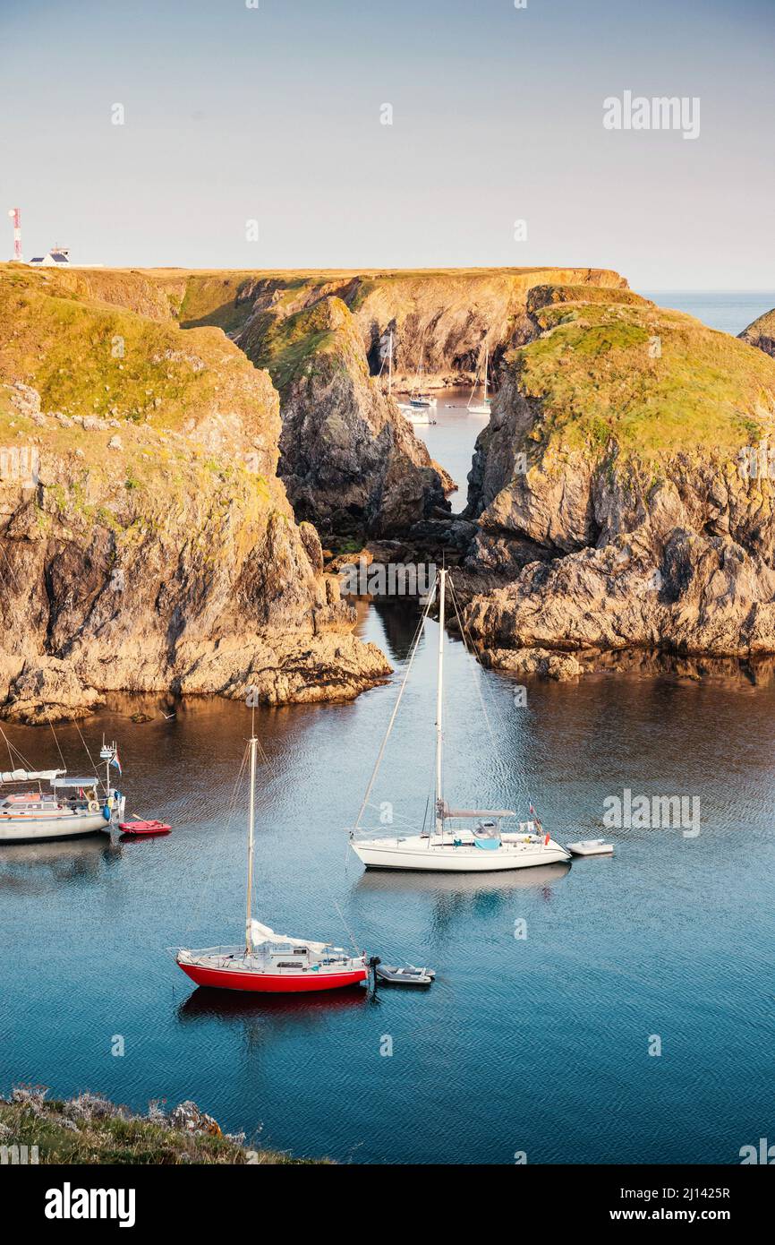 Die ruhigen Buchten an der felsigen Küste der Insel Belle Ile en Mer bieten einen geschützten Ankerplatz für viele Segelboote im ruhigen Sonnenuntergang. Stockfoto