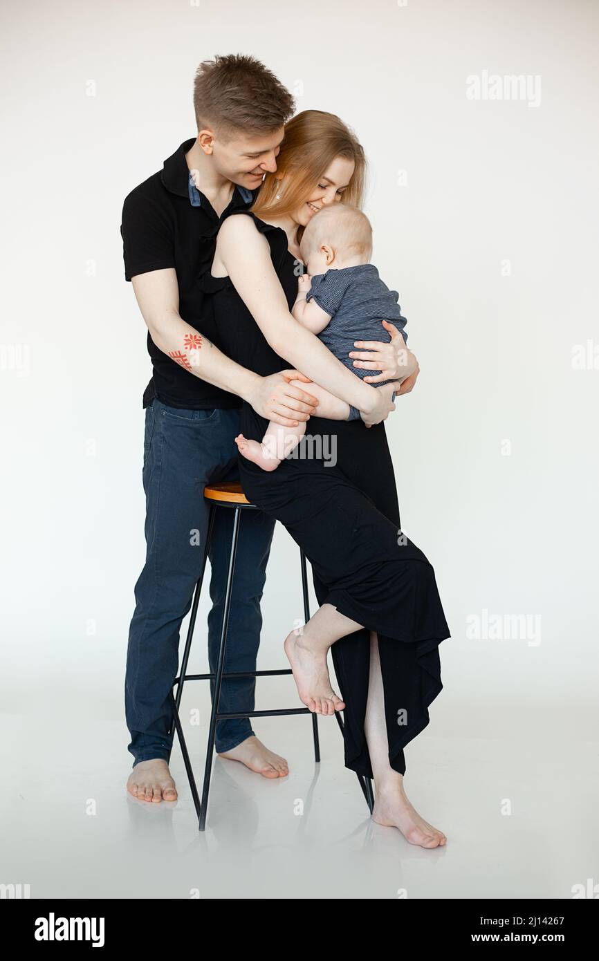 Vertikale Aufnahme Porträt von glücklichen Ehegatten, barfuß Familie, Mann, Frau, Kind auf Barstuhl. Aussehendes Kind. Volle Länge Stockfoto