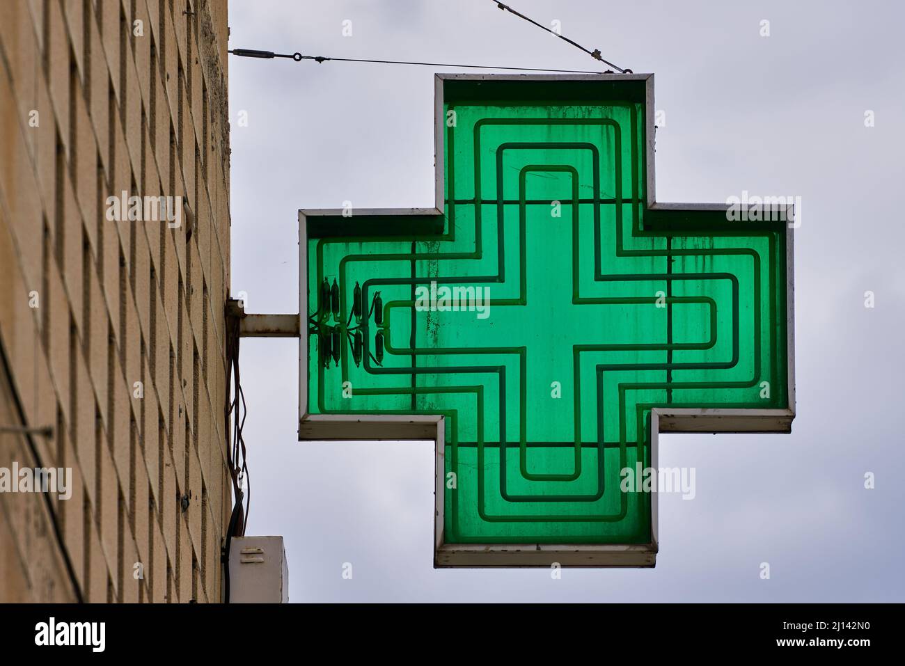 Grünes kreuzförmiges Apothekenschild mit Himmel im Hintergrund Stockfoto