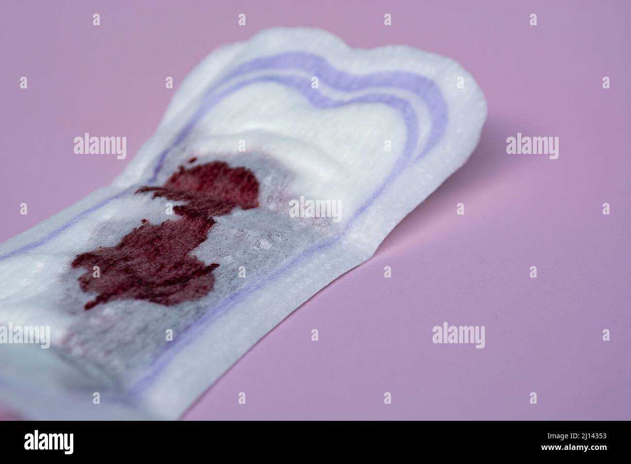 Menstruationsblut auf einer Sanitäranlage auf rosa Hintergrund. Hygieneschutz für Frauen. Raummuster kopieren. Flach liegend. Stockfoto