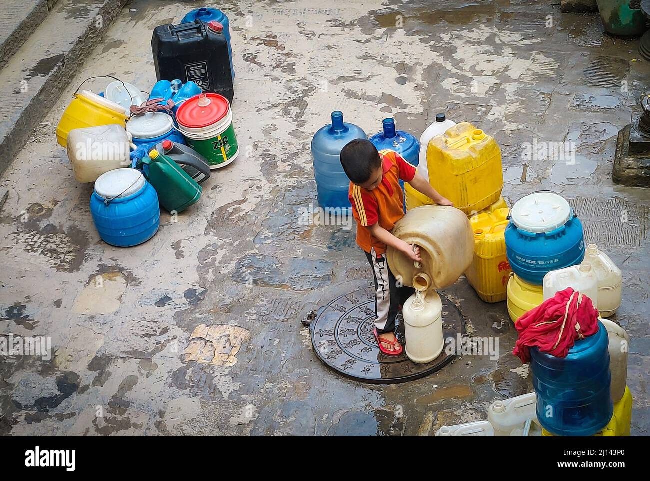 Kathmandu, Bagmati, Nepal. 22. März 2022. Ein kleines Kind gießt Wasser in ein anderes Glas, nachdem es aus einem traditionellen Steinhahn in Kathmandu, Nepal, am 22. März 2022, dem Weltwassertag, gefüllt wurde. Die Menschen im Kathmandu-Tal stehen aufgrund der zunehmenden Bevölkerung und Urbanisierung immer noch vor dem Problem der Trinkwasserknappheit. (Bild: © Sunil Sharma/ZUMA Press Wire) Stockfoto