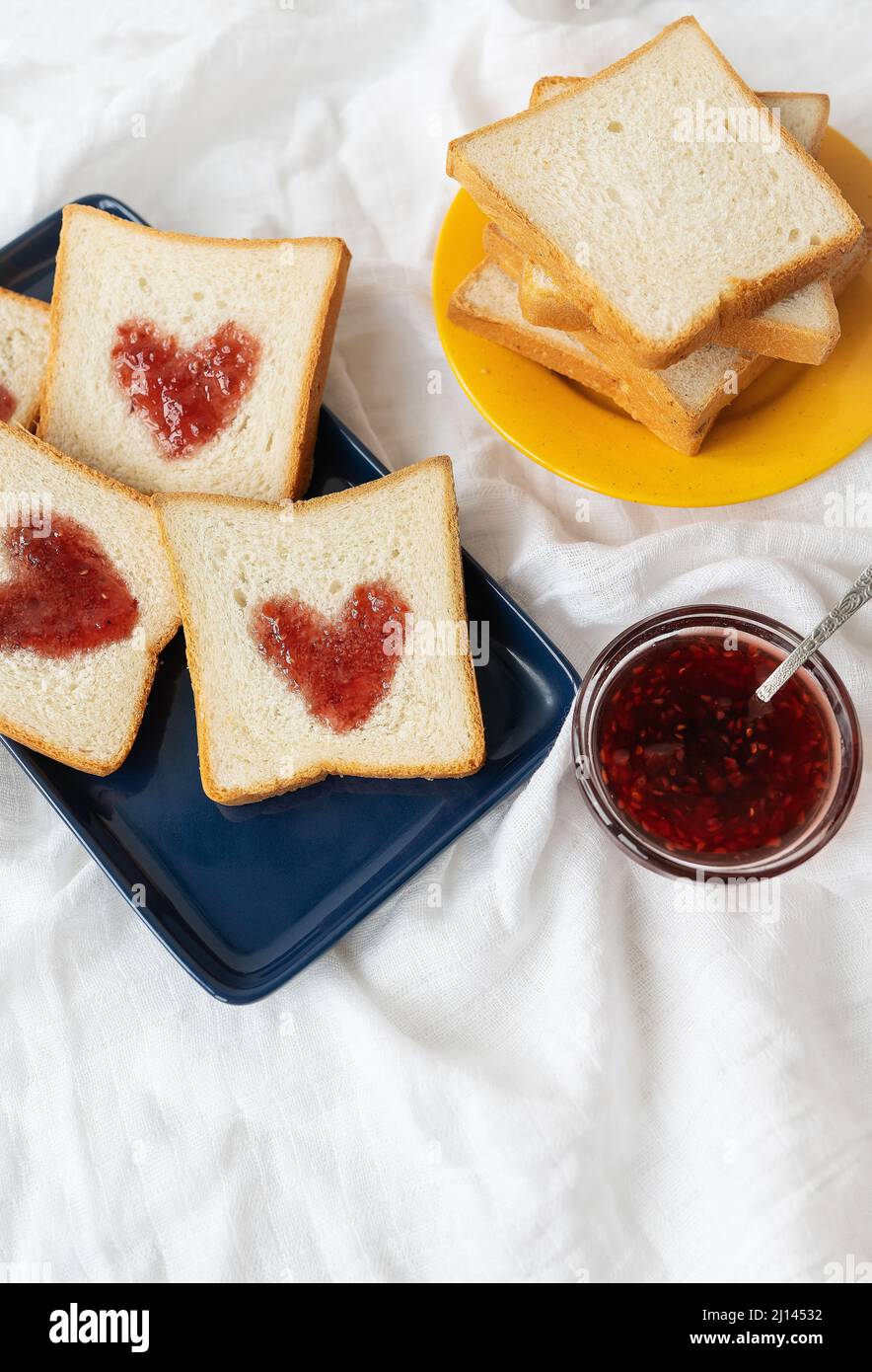 Toast, auf dem das Herz aus Marmelade besteht. Überraschungsfrühstück im Bett. Romantik zum Valentinstag Stockfoto