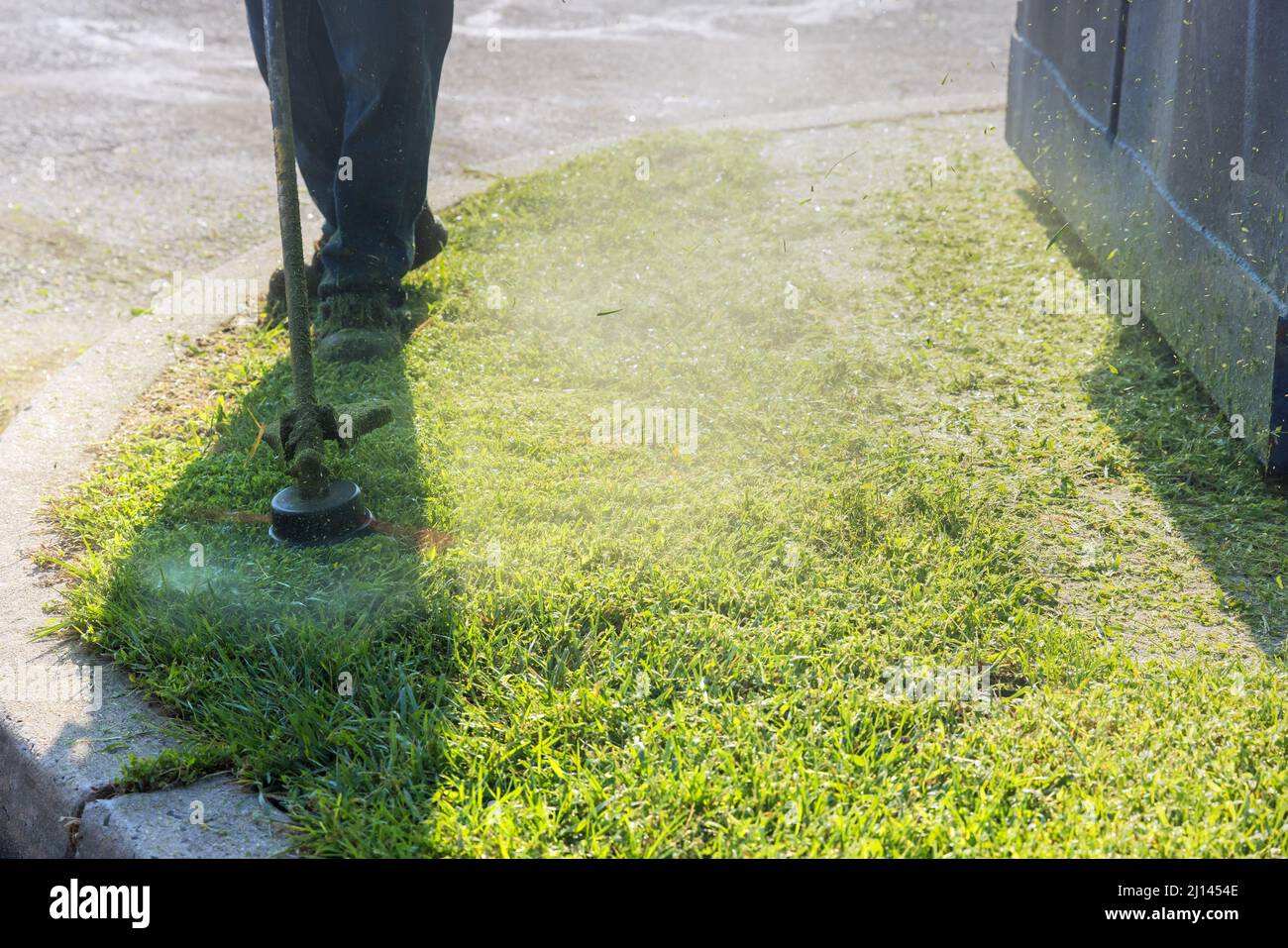 Saisonarbeiter Mann Rasenmäher Schneiden Gras am Straßenrand Stockfoto