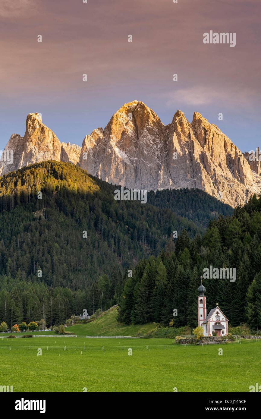 Kirche St. Johann in Ranui mit Geisterdolomien hinter dem Dorf bei Sonnenuntergang, Villnösser Tal, Südtirol, Italien Stockfoto