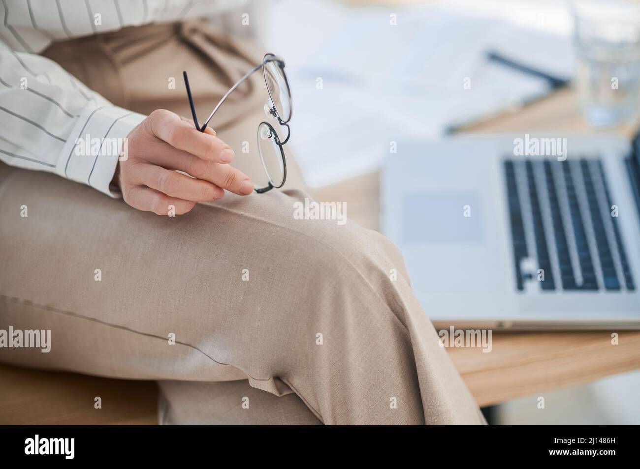 Nahaufnahme einer Frau in beigefarbenen Hosen, die auf dem Tisch sitzt Stockfoto