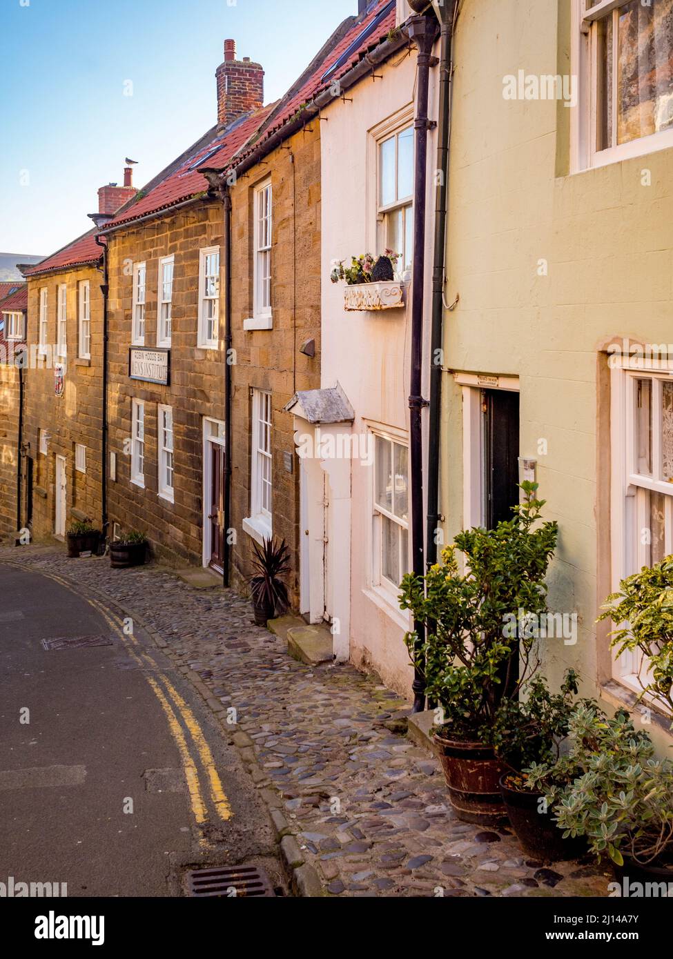 Eine Reihe traditioneller Terrassenhäuser an einer steilen Straße Robin Hoods Bay, North Yorkshire. Stockfoto