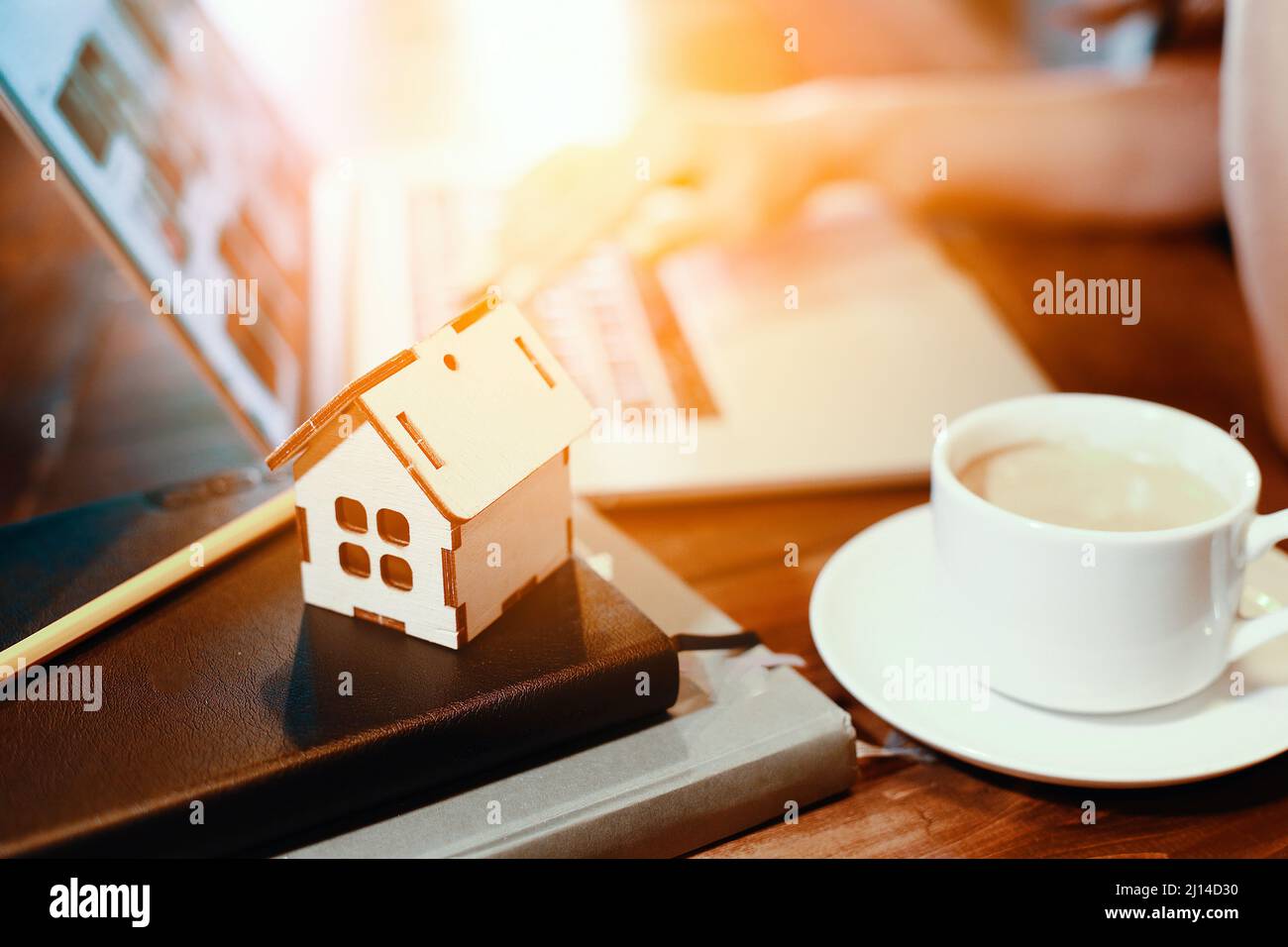 Modell des Holzhauses auf dem Hintergrund des Laptops. Konzept der Immobiliensuche im Internet. Kauf oder Versicherung von Wohnraum. Hintergrund. Stockfoto