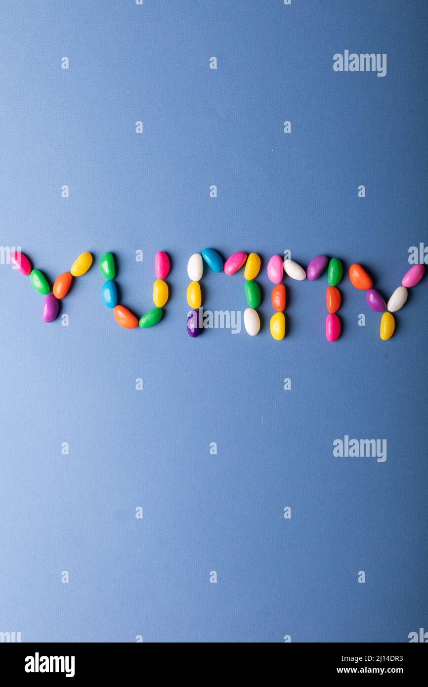 Direkt über der Ansicht von leckeren Wort aus bunten Süßigkeiten auf blauem Hintergrund über Kopierraum angeordnet Stockfoto