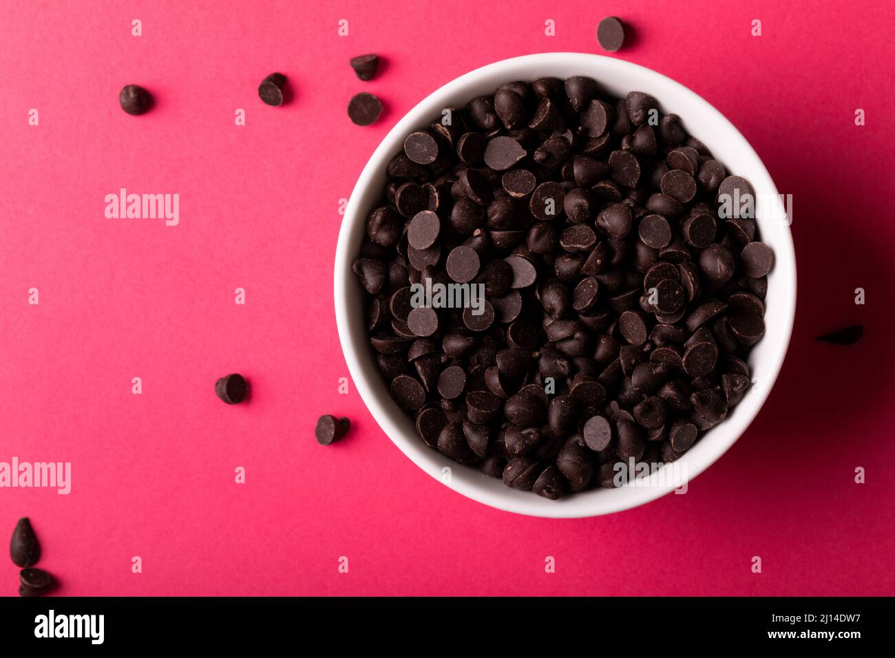 Blick von oben auf frische Schokoladenchips in der Schüssel auf rosa Hintergrund Stockfoto