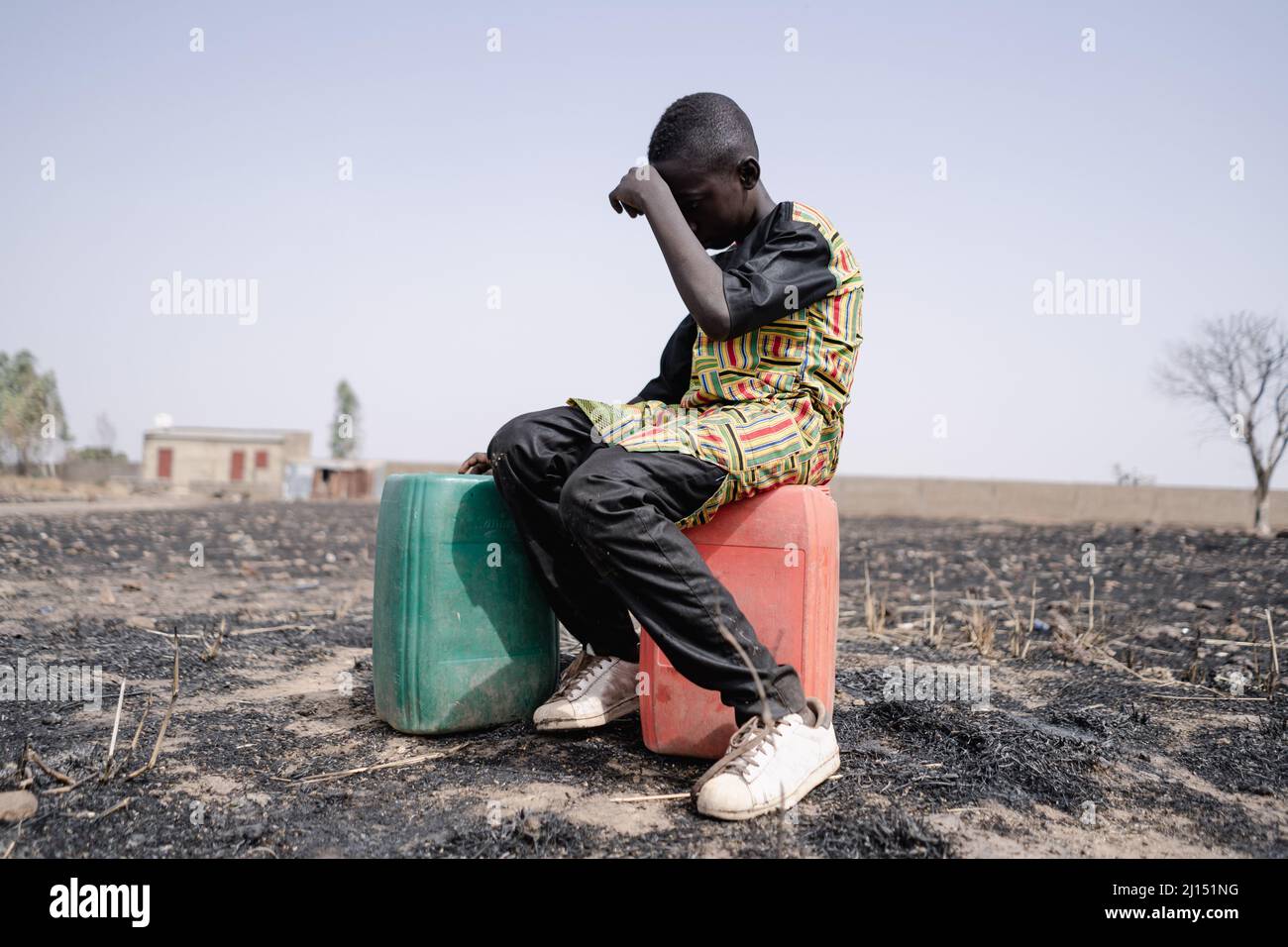 Afrikanischer Teenager wurde für lange Strecken angespannt, um sauberes Wasser zu sammeln.Symbol für Wasserknappheit. Stockfoto