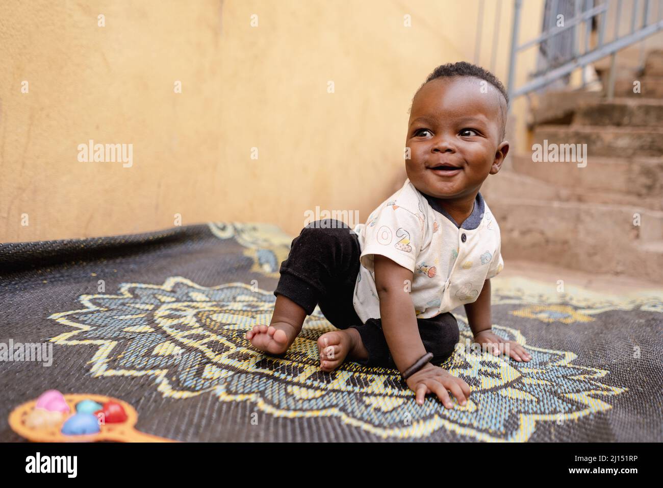 Schöne niedliche afrikanische Baby junge, glücklich spielen auf einem Teppich in einem Kindergarten. Stockfoto