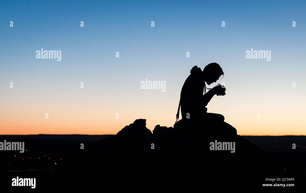 Außenbild des Fotografen, der vor Sonnenaufgang die Kamera anschaut Stockfoto