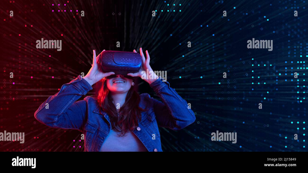 Hispanische Frau mit Virtual-Reality-Brille mit digitaler Technologie, die 3D im Cyberspace mit blauem und rotem Licht Spaß hat Stockfoto