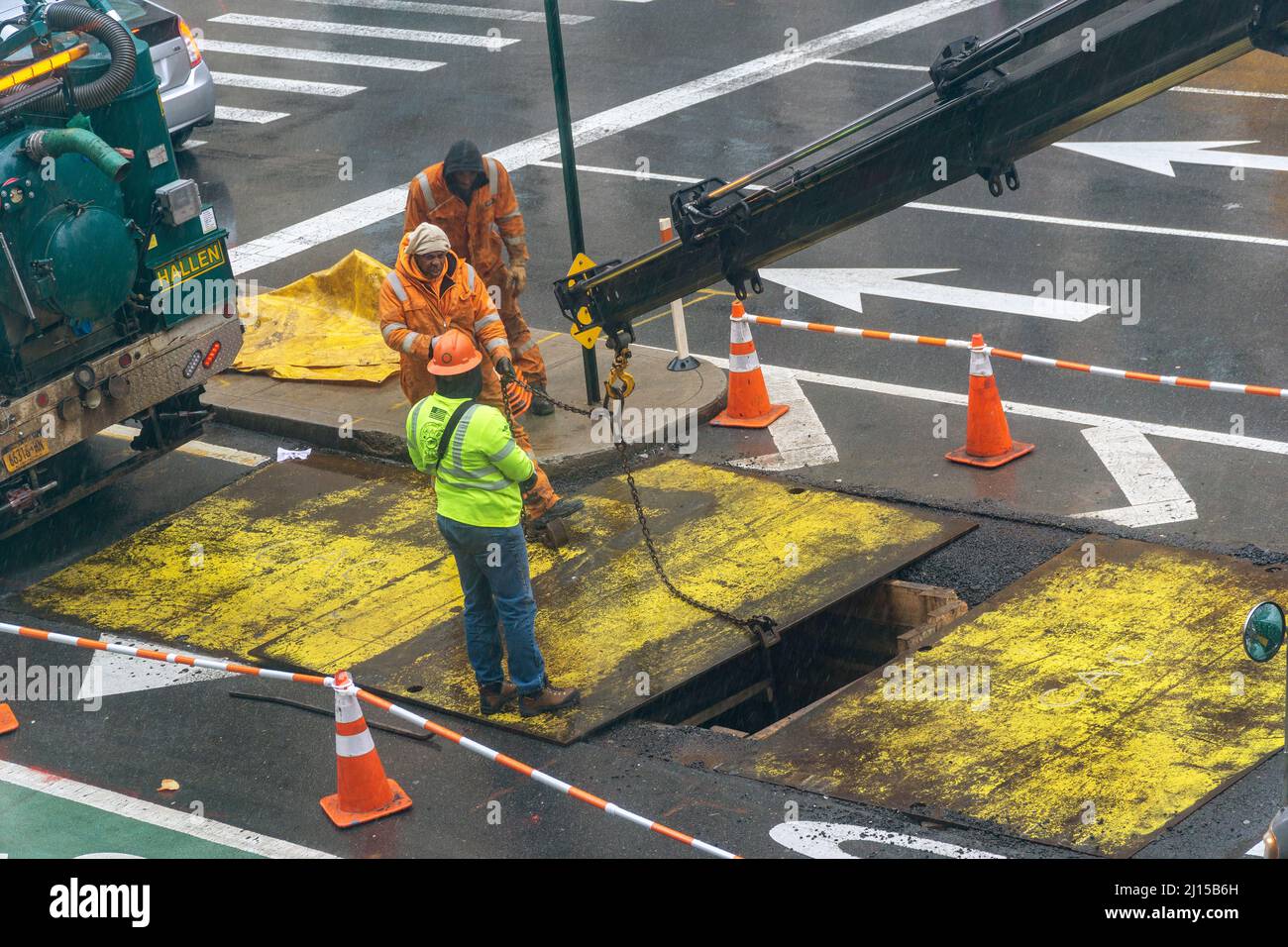 Arbeiter ersetzen eine Stahlplatte über der Fahrbahn, nachdem sie am Mittwoch, dem 9. März 2022, in der Ninth Avenue in Chelsea in New York unterirdisch gearbeitet haben. (© Richard B. Levine) Stockfoto