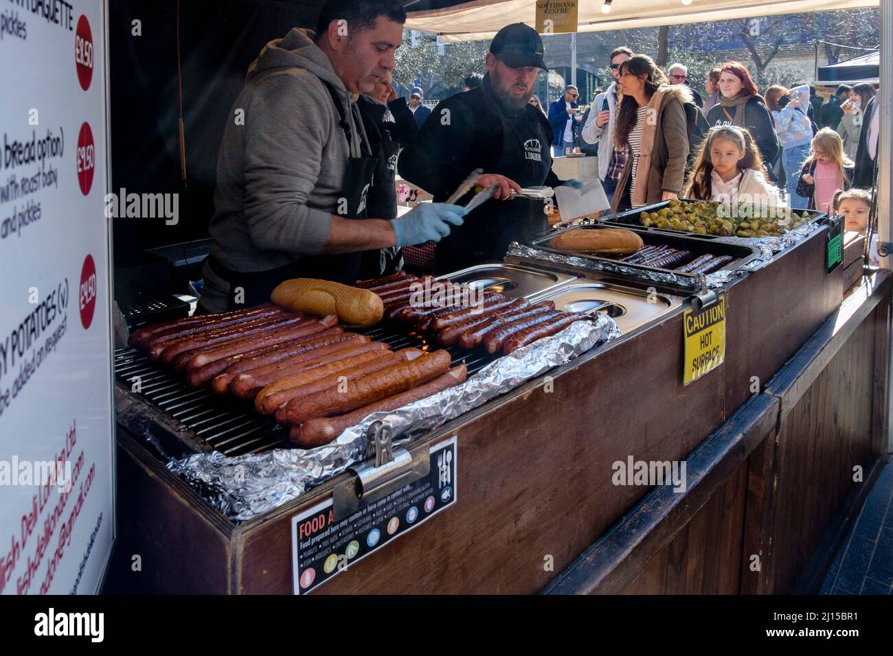 Wurstbaguettes werden am polnischen Deli-Imbissstand im Southbank Centre Food Market, South Bank, London, Großbritannien, zubereitet. Stockfoto