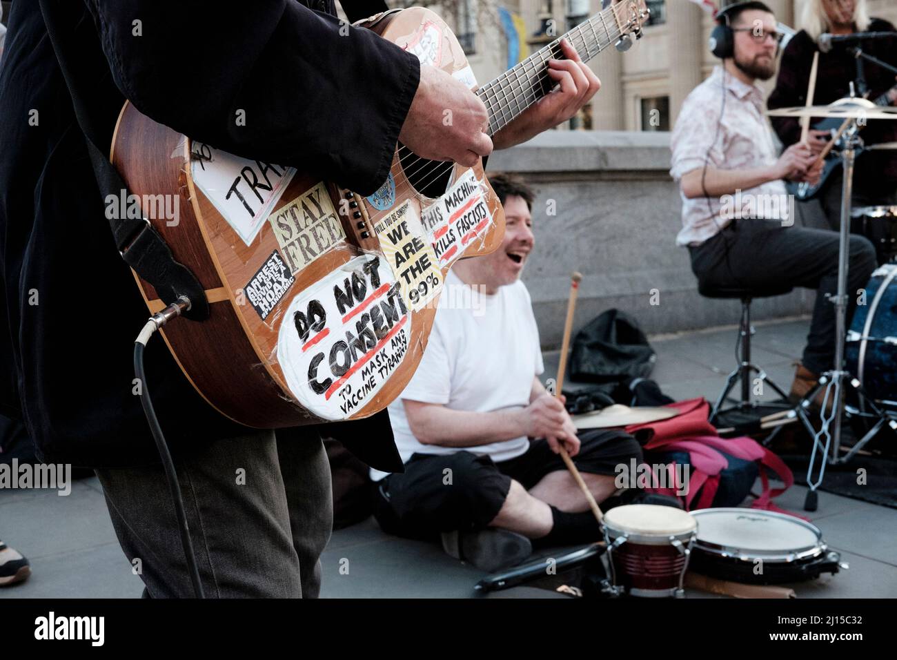 Musiker mit Anti-Corona-Virus-Impfstoff und Masken-Tragestatements auf seiner Gitarre tritt bei einer „Freedom“-Kundgebung im Zentrum von London, Großbritannien, auf. Stockfoto