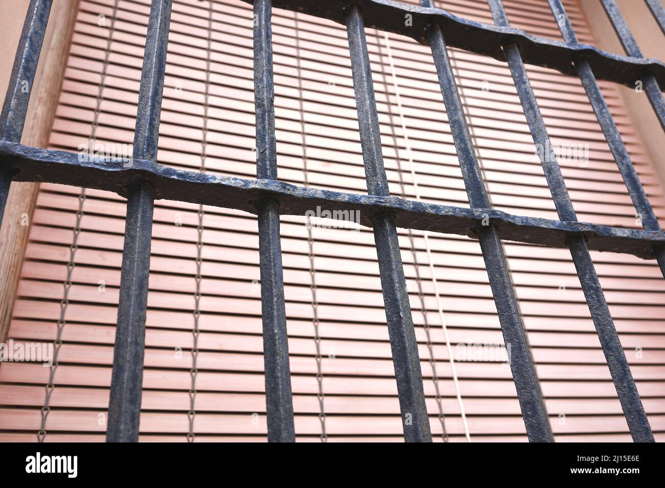 Detail eines alten geschmiedeten Zauns auf einem antiken Fenster mit einem Fensterladen Stockfoto