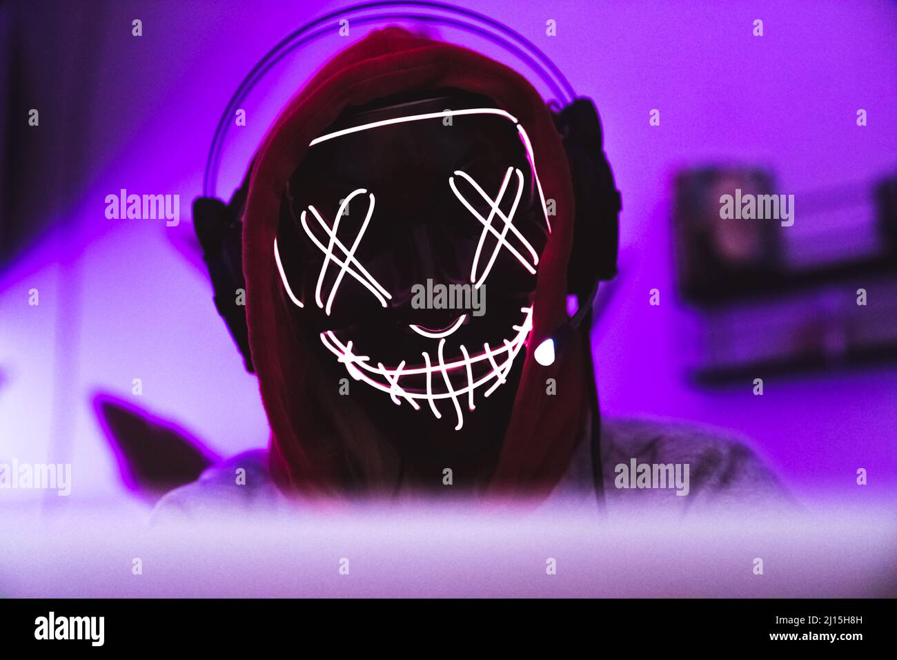 Identität im Internet. Maskierter anonymer Hacker mit Kopfhörern und Hoodie. Hochwertige Fotos Stockfoto