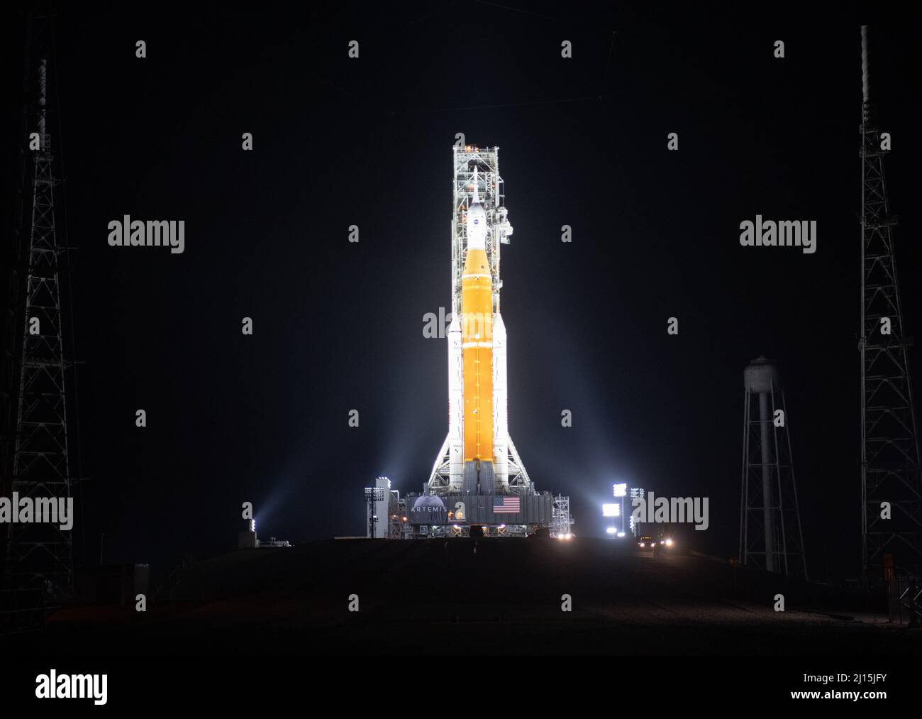 Die NASA-Rakete Space Launch System (SLS) mit der Orion-Sonde an Bord wird von Scheinwerfern auf einer mobilen Trägerrakete am Launch Complex 39B, Freitag, 18. März 2022, beleuchtet, nachdem sie zum ersten Mal am Kennedy Space Center der NASA in Florida auf die Startfläche ausgerollt wurde. Vor dem Artemis I-Flugtest der NASA werden die vollständig gestapelte und integrierte SLS-Rakete und die Orion-Raumsonde im Launch Complex 39B einer Nassprobe unterzogen, um die Systeme zu verifizieren und Countdown-Verfahren für den ersten Start zu üben. Foto: (NASA/Joel Kowsky) Stockfoto