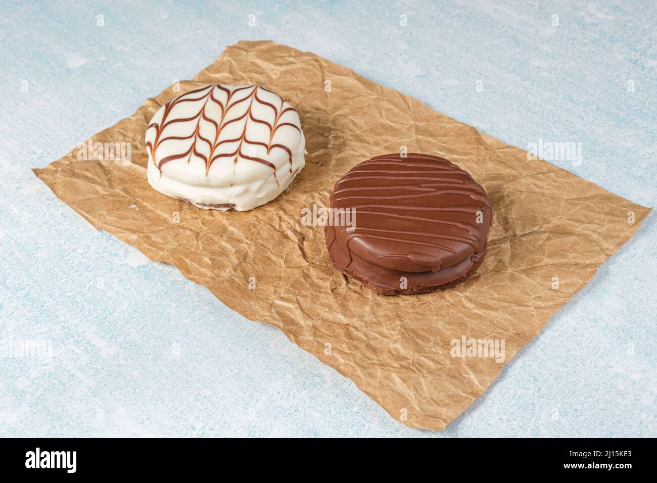 Brasilianische Honigkuchen, einer traditionell und der andere mit weißem Schokoladenfrosting, auf einem Blatt braunem Papier. Stockfoto
