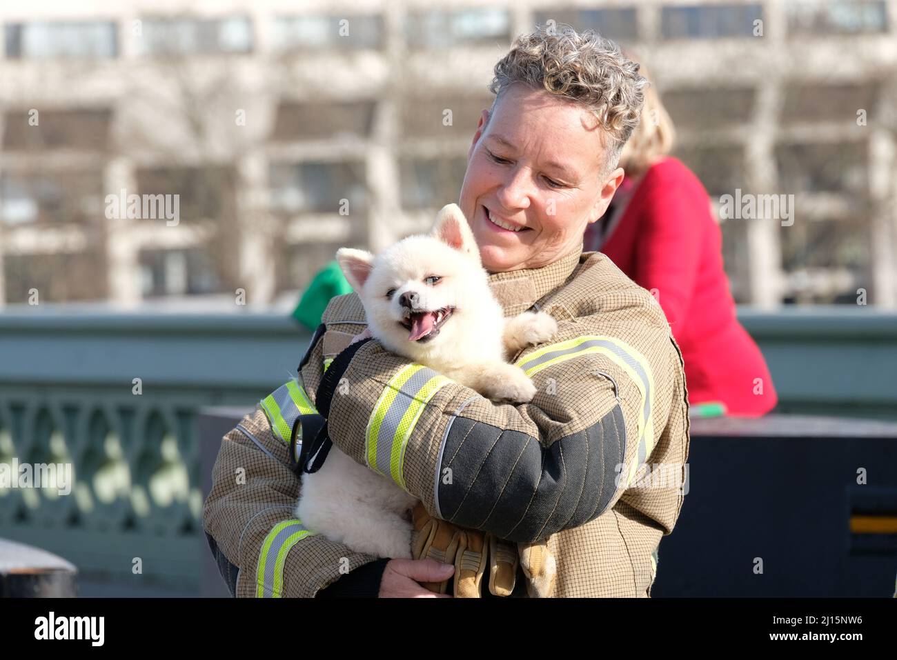 London, Großbritannien. Eine Feuerwehrfrau in Uniform kuschelt mit einem Welpen nach einem Terroranschlag Gedenkgottesdienst. Stockfoto