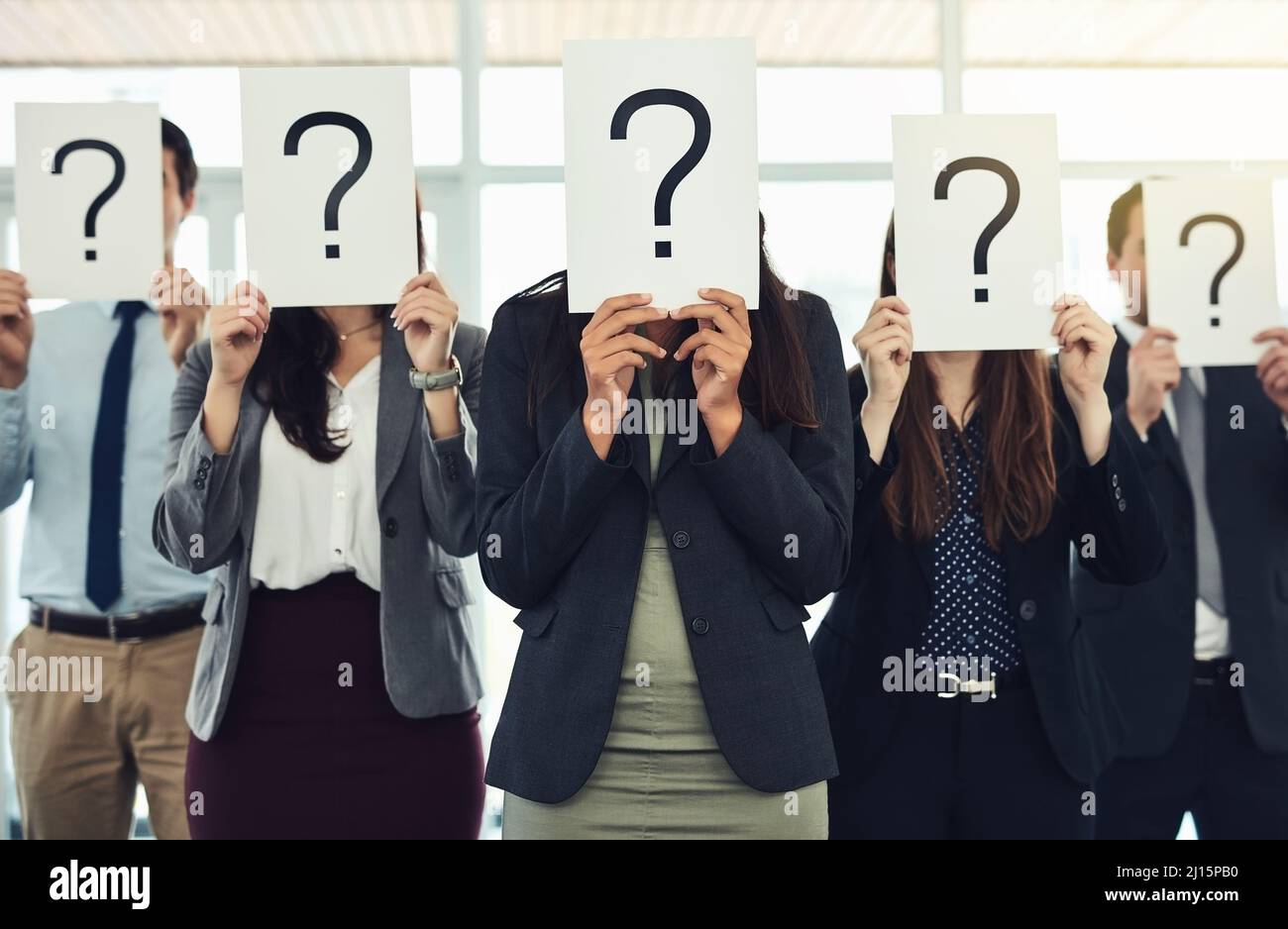 Haben Sie Antworten, weil wir Fragen haben? Aufnahme einer Gruppe von Geschäftsleuten, die Fragezeichen vor ihren Gesichtern halten. Stockfoto